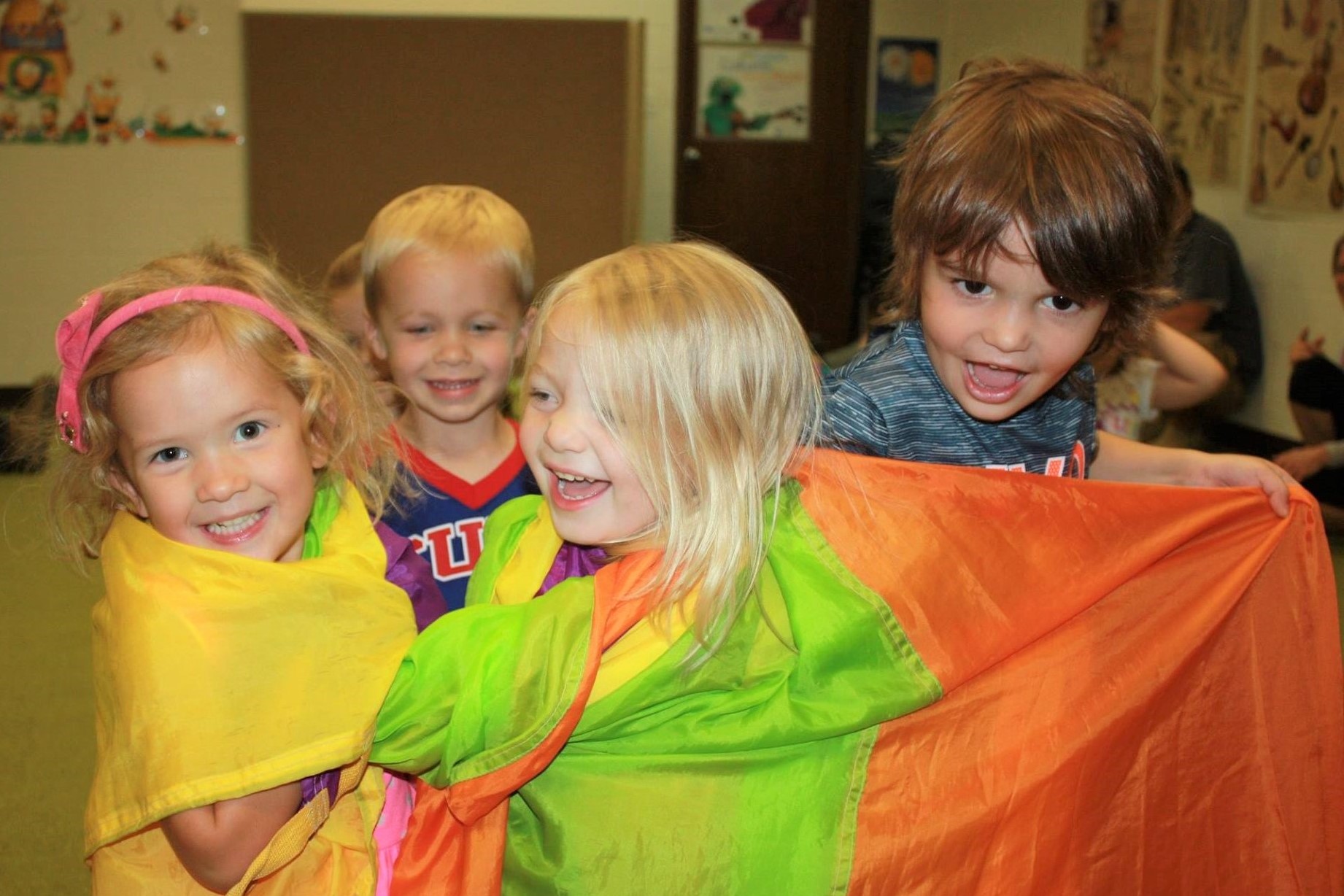 three and four year old children playing with a parachute